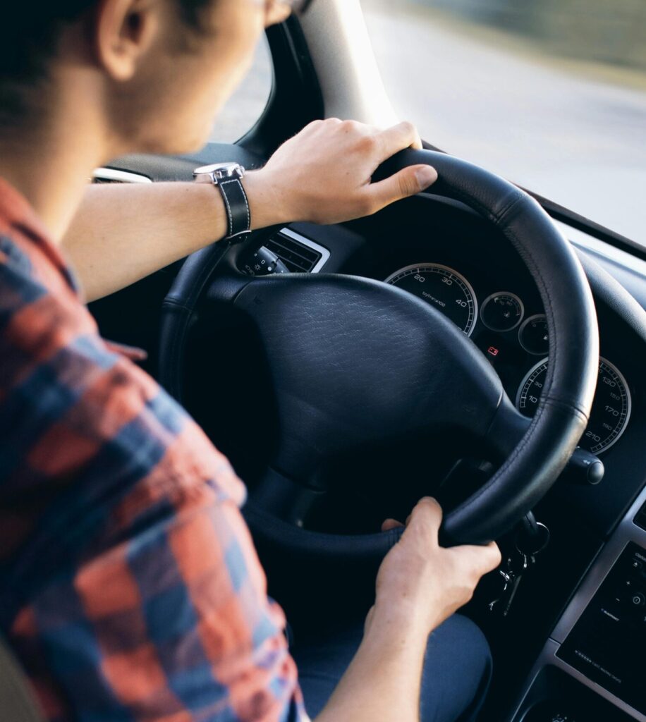 Close-up view of a man driving a modern car, showing dashboard and steering details.