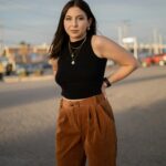 pexels-photo-16346899-16346899 Woman in black crop top and brown pants posing outdoors at sunset.