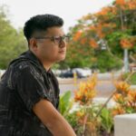 pexels-photo-31965990-31965990 Relaxed man with glasses in a Yucatan park surrounded by vibrant flora.